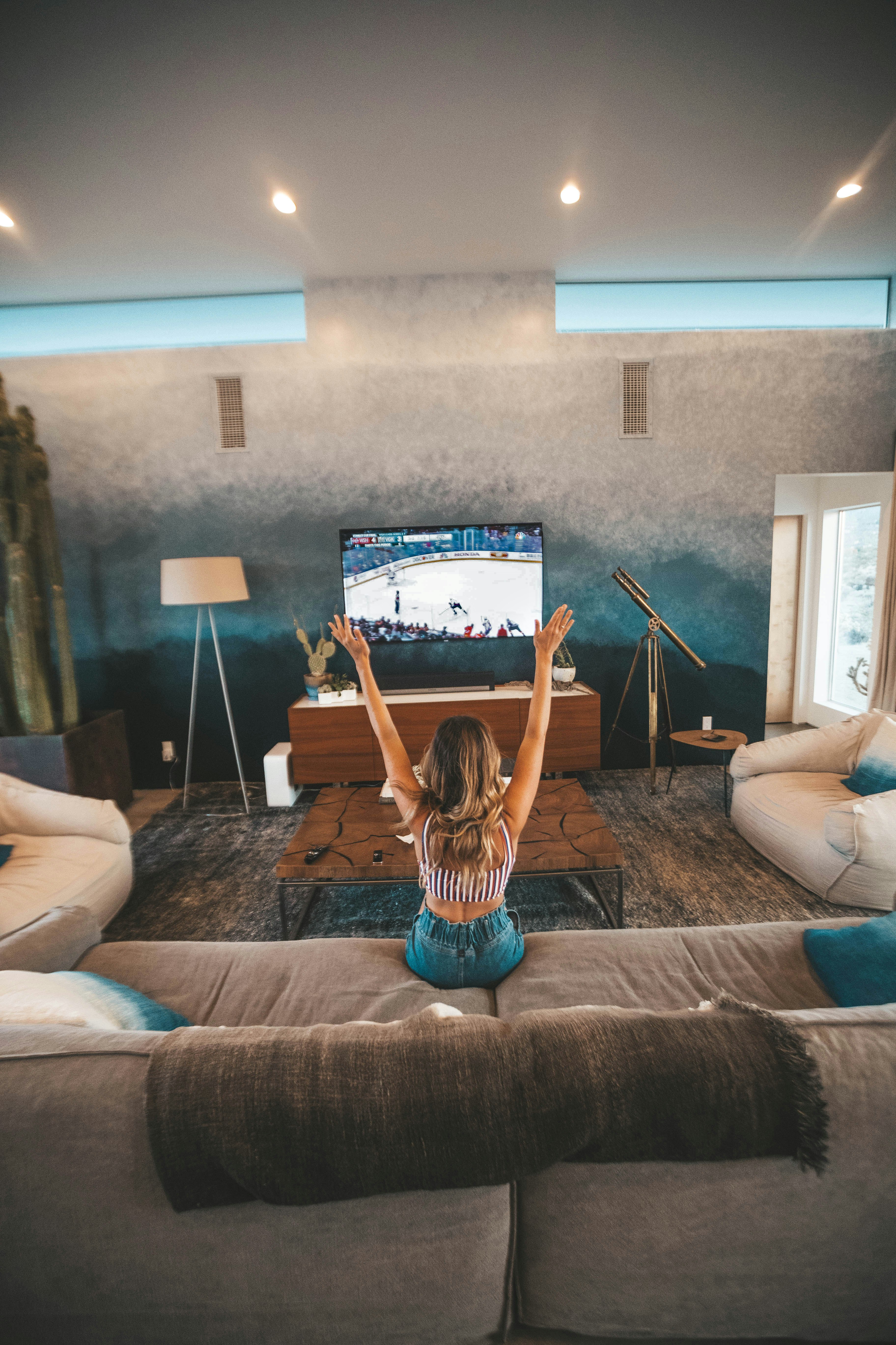 woman sitting on brown sofa watching TV